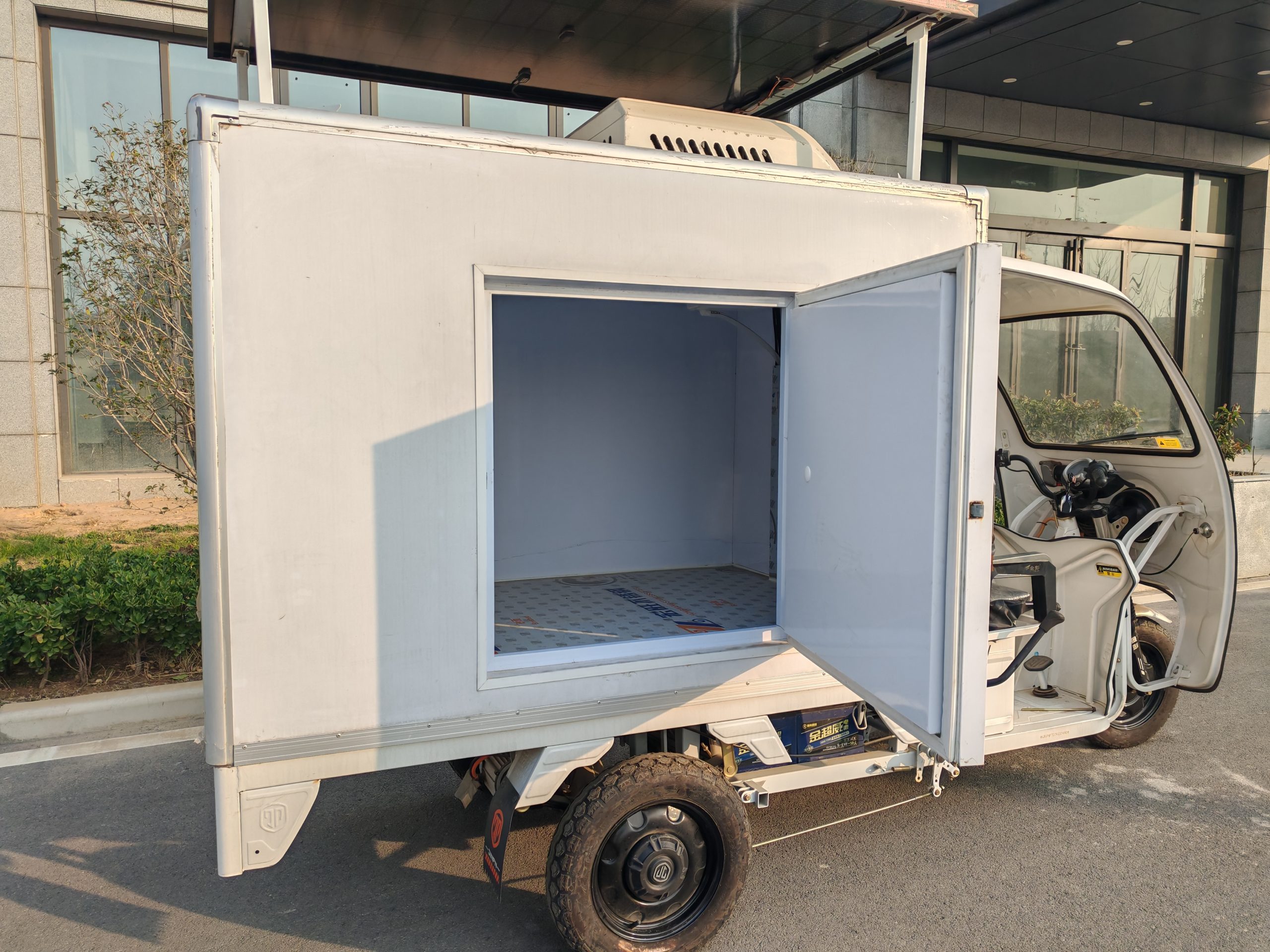 Open insulated cargo box on a white refrigerated tricycle